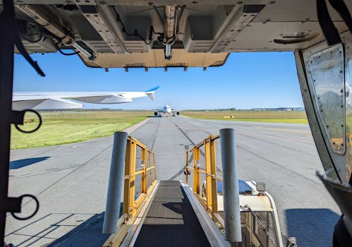 A sunny day on the tarmac with a view from an aircraft cargo door, showcasing other planes in the background.