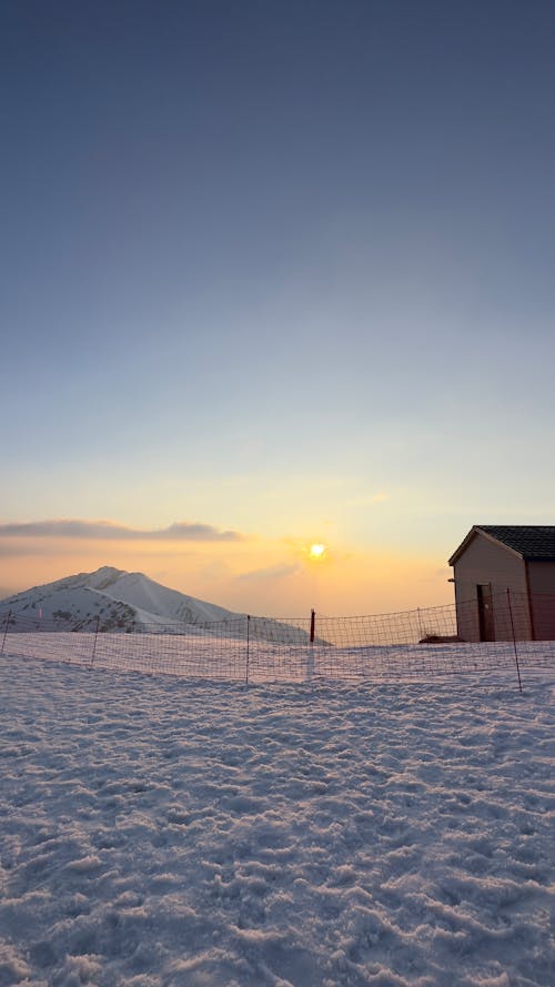 Landscape of a Snowy Field and a Mountain in the Background at Sunset