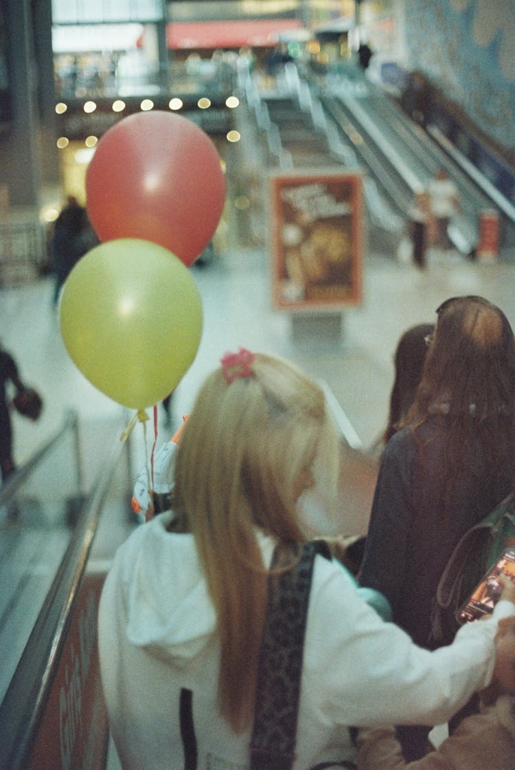 People With Balloons On Escalator In Mall