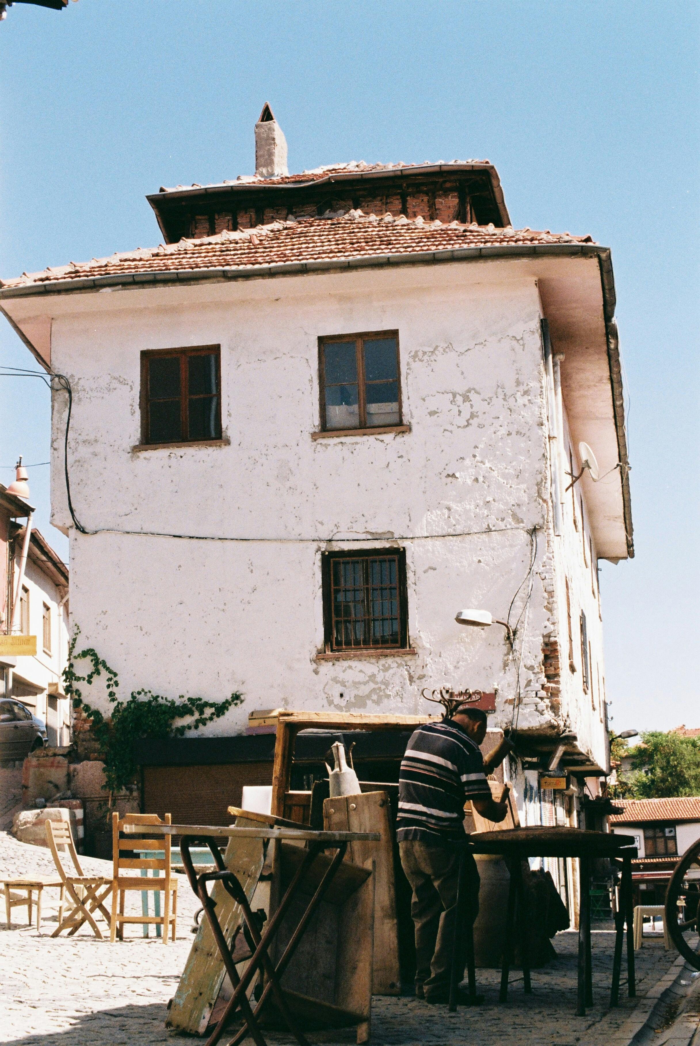 A carpenter works on wooden boards in a sunlit urban area in Ankara, Turkey.