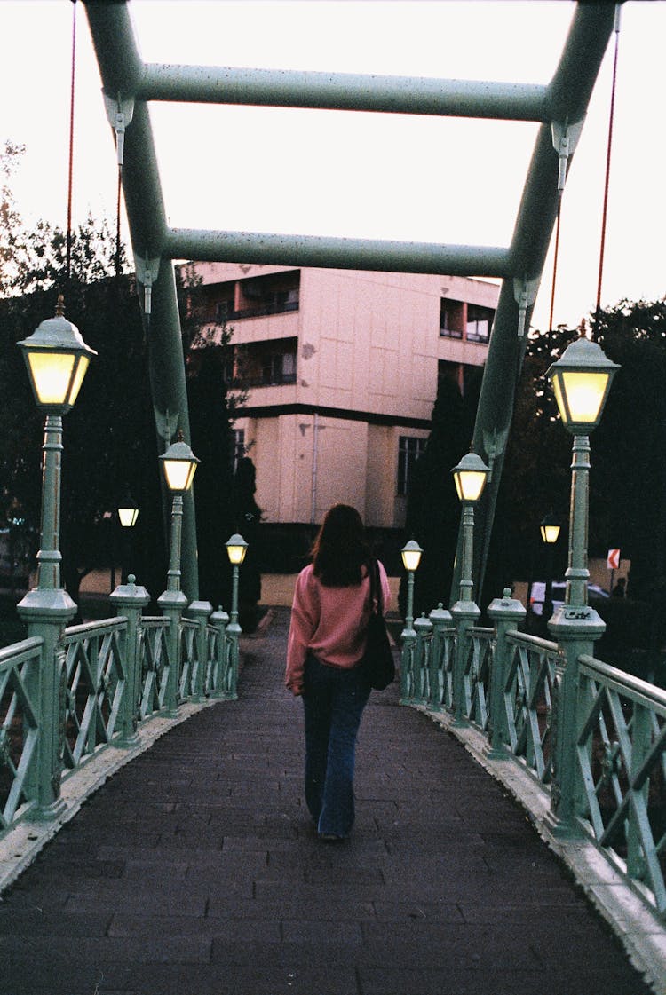 Woman Walking On Bridge On Sunset