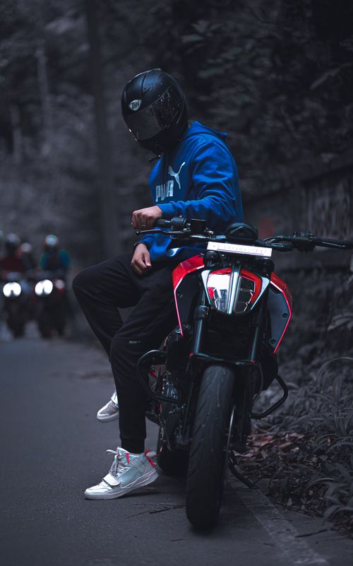 Free A motorcyclist in a blue hoodie sitting on a stylish motorcycle at twilight with a mysterious look. Stock Photo