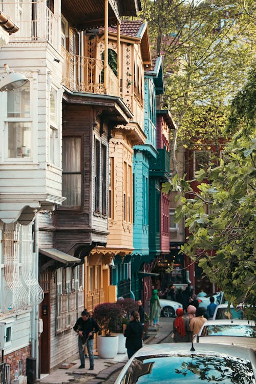 People Walking between a Row of Houses and Cars Parked along the Street