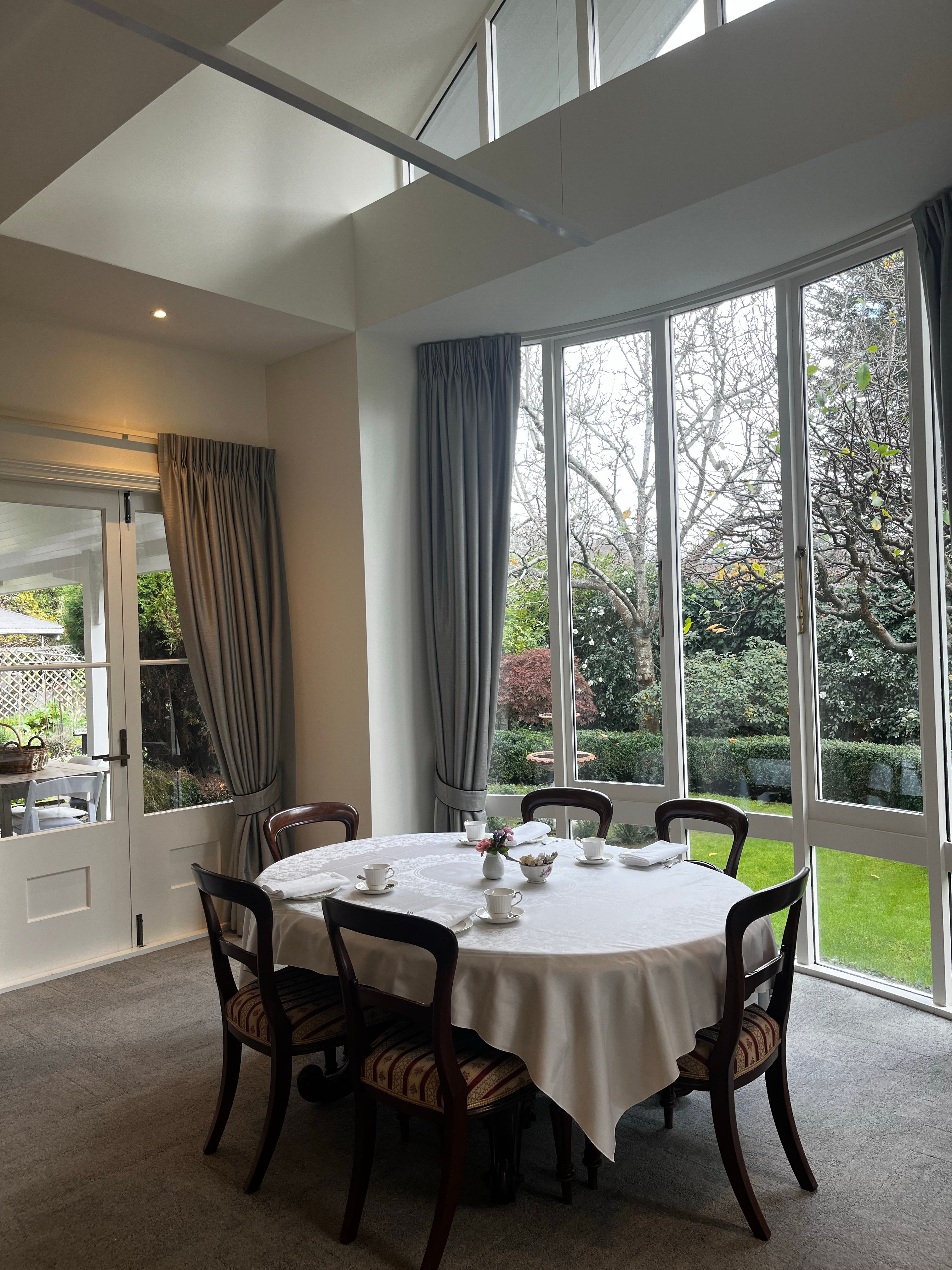 A table set for dining beside tall glazed doors onto a garden