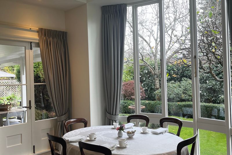 A table set for dining beside tall glazed doors onto a garden