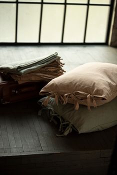 Warm, inviting cushions on a wooden floor with natural light through a large window.