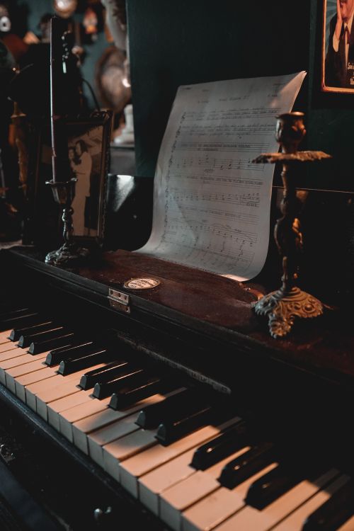 Free A vintage piano adorned with sheet music and candlestick holders, capturing a nostalgic ambiance. Stock Photo