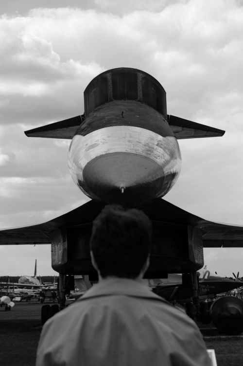 Free Man observing a futuristic aircraft in a black and white setting, conveying an industrial and urban mood. Stock Photo