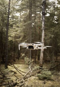 Compact drone flying through a dense green forest, showcasing technology and nature.
