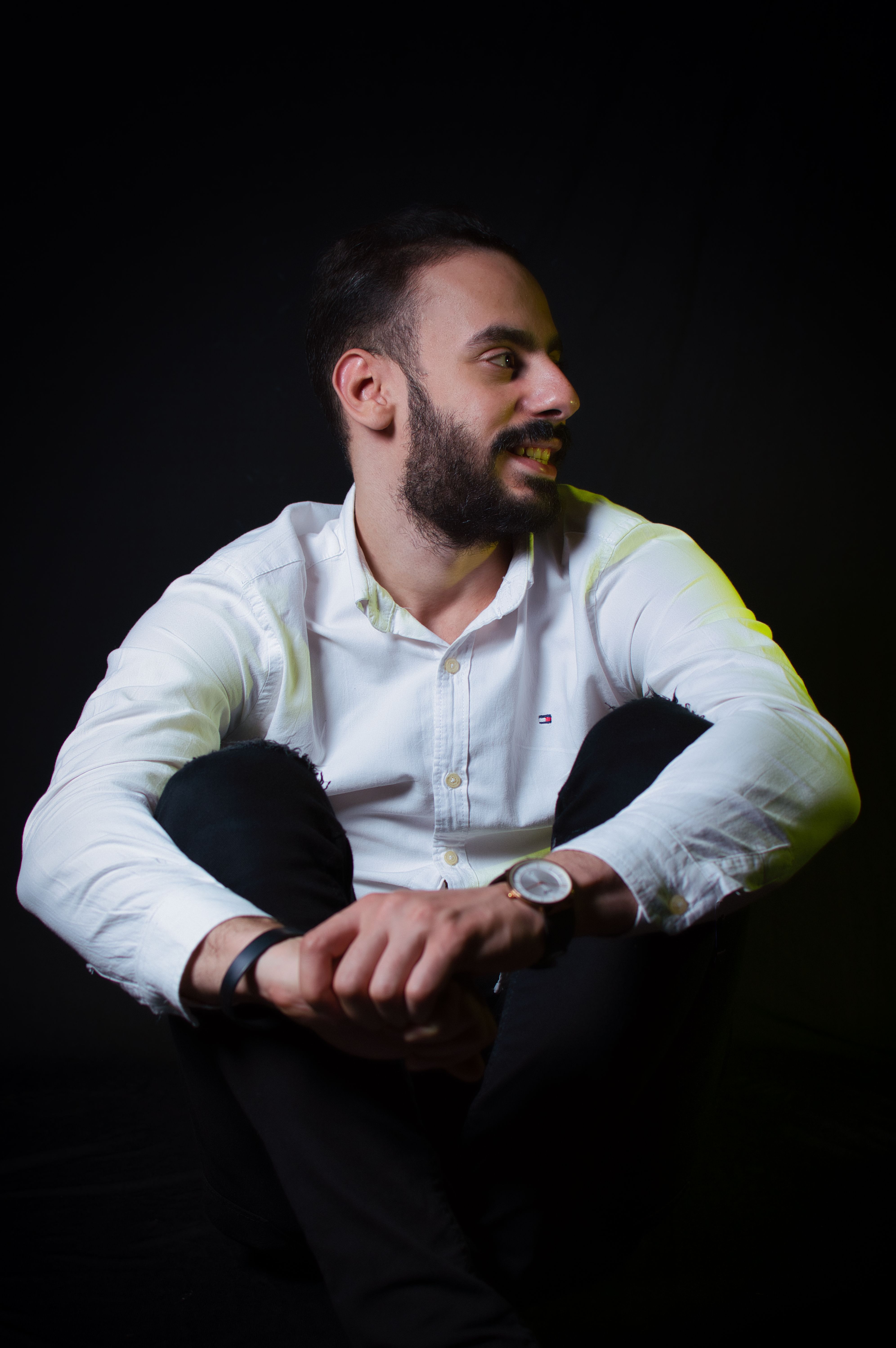 Portrait of a bearded man sitting with relaxed posture in a studio setting.