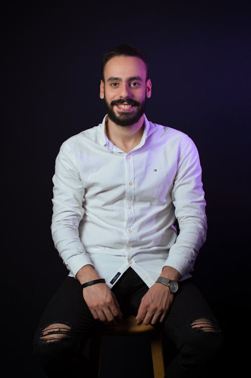 Portrait of Smiling Bearded Man Sitting on Stool in Studio