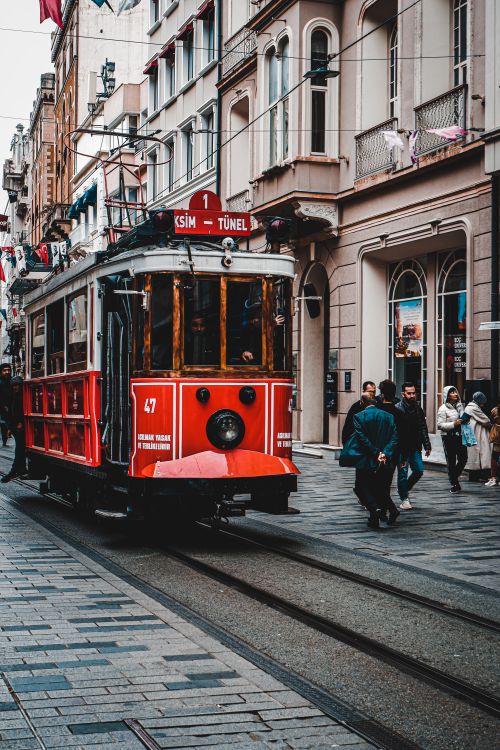 Free Historic red tram navigating through a busy street in Istanbul, Turkey, with pedestrians and urban cityscape. Stock Photo