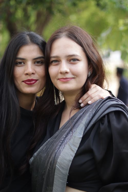 Free Two women with dark hair smiling and posing outdoors in a lush garden setting, exuding warmth and friendship. Stock Photo