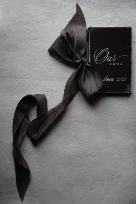 A black and white wedding vows booklet elegantly tied with a satin ribbon, 2023 edition.