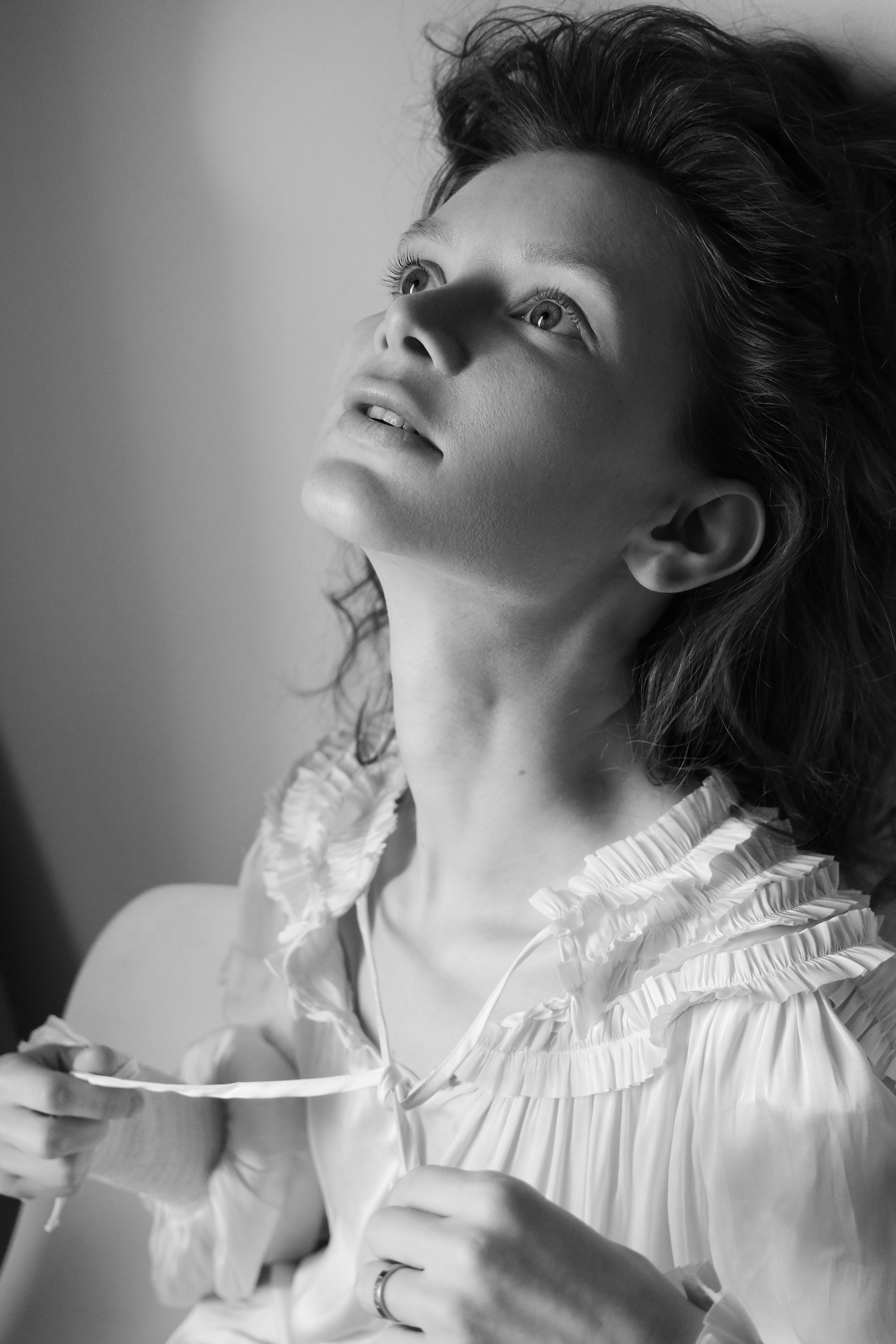Elegant black and white portrait of a young woman gazing upward, exuding a serene mood.