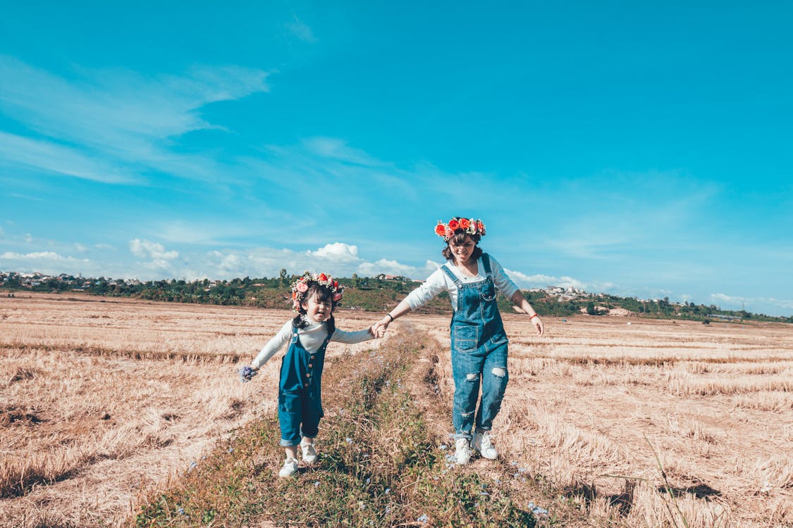 Woman and Girl Doing Hand in Hand Whole Walking on Grass Field