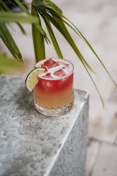 Colorful cocktail with lime on a textured surface, perfect for summer gatherings.