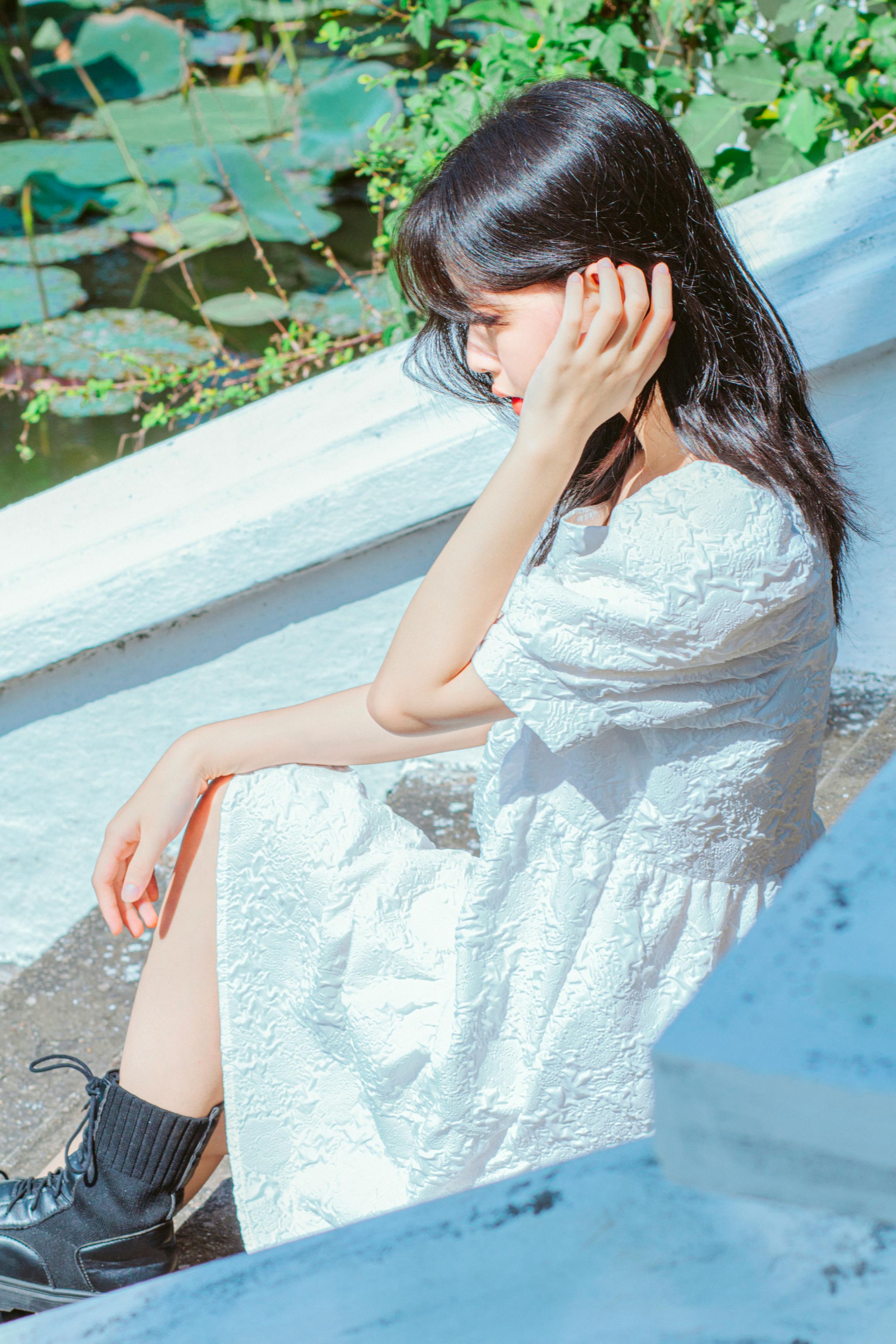 photo of a beautiful young woman sitting in a summer dress