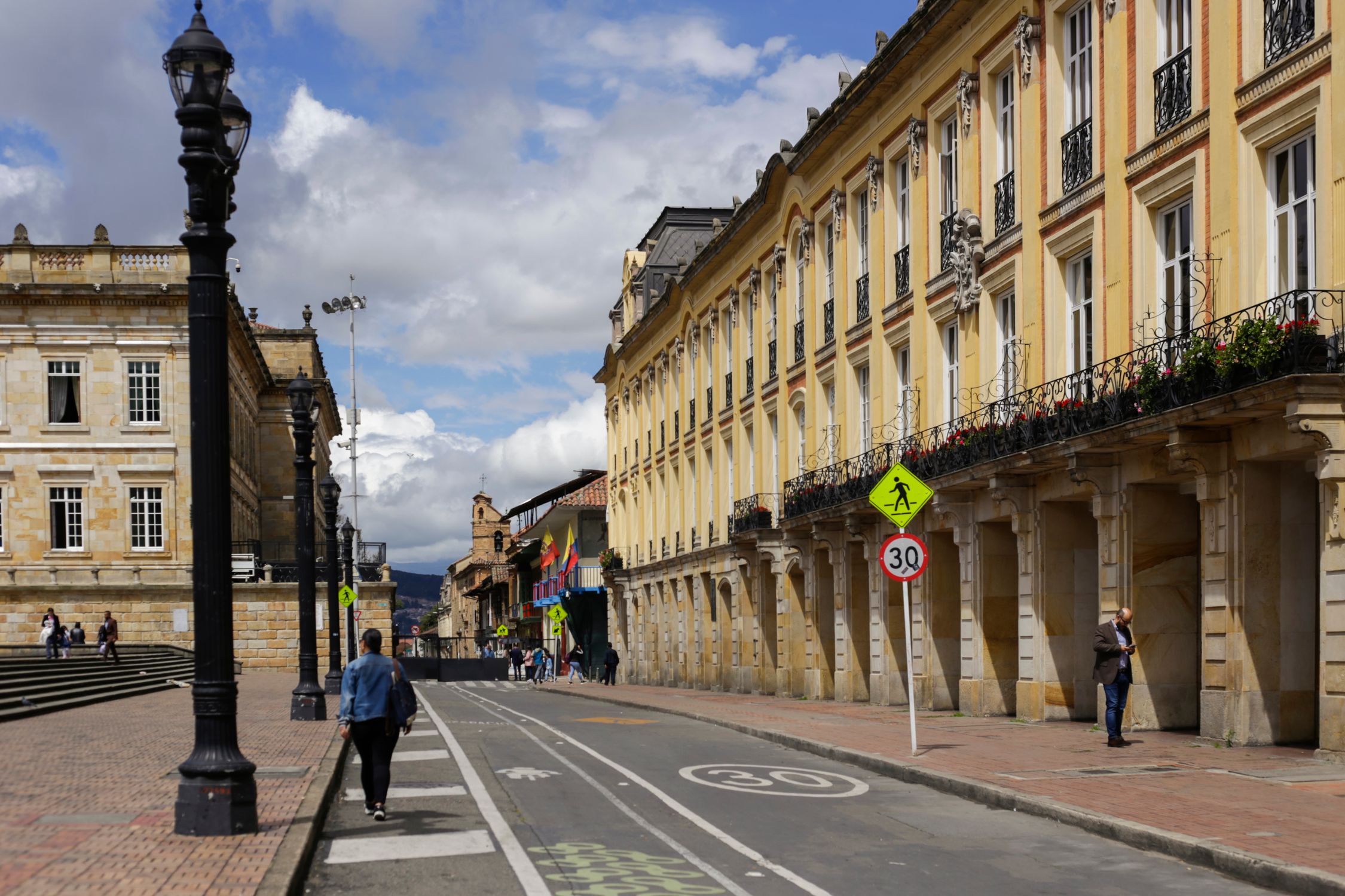 A vibrant day on a historic street in Bogota, showcasing colonial architecture.