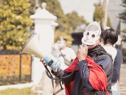 People in Masks with Loudspeakers on Street Protest