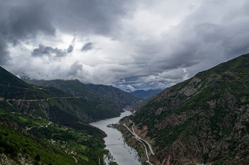 Aerial View of a River Flowing in a Valley under a Cloudy Sky 