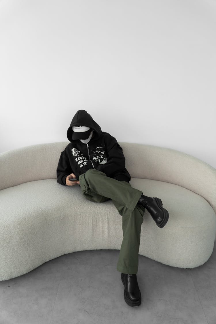 Young Person In A Trendy Outfit Sitting On A Couch 