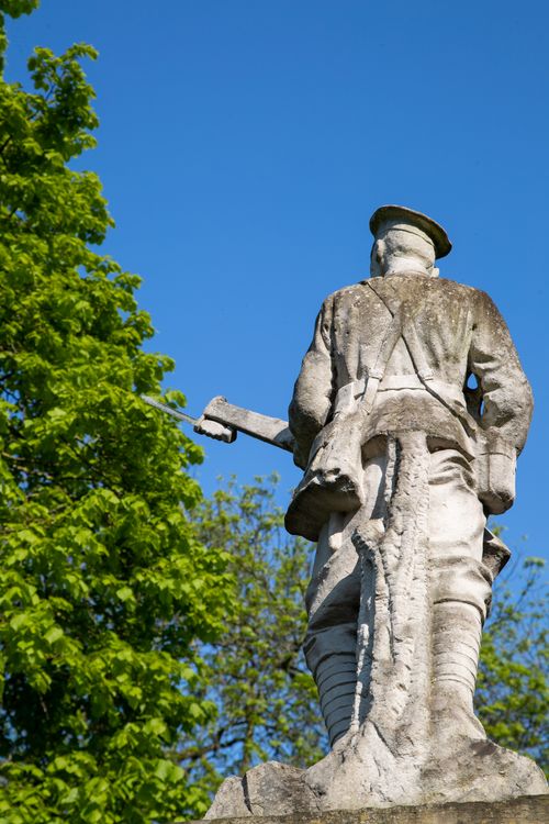 Free A rear view of a stone soldier statue against a clear blue sky, symbolizing commemoration. Stock Photo