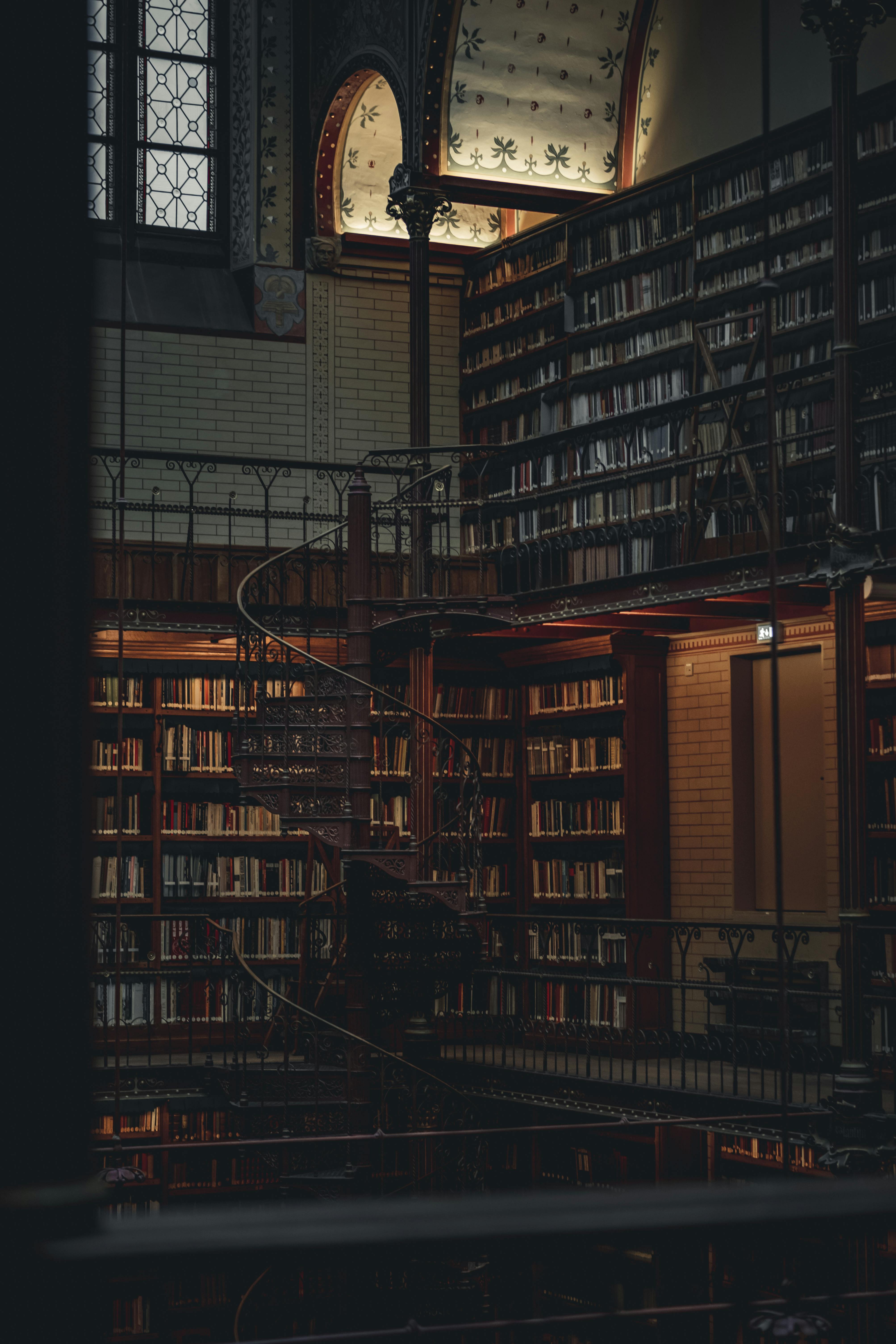 Moody interior shot of Rijksmuseum Library with spiral staircase and bookshelves in Amsterdam.