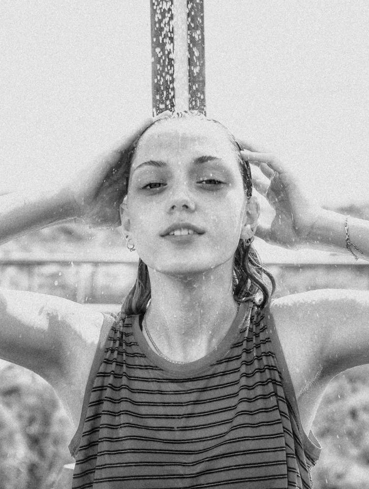 Black And White Photo Of A Young Woman Standing Under An Outdoor Shower