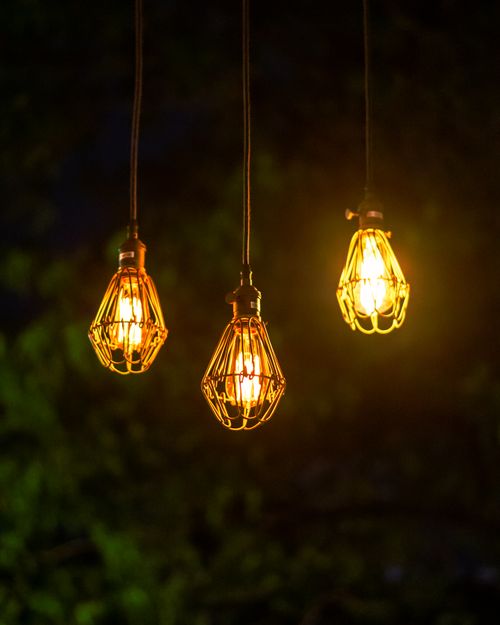 Free Three illuminated string lights hanging in a garden at night Stock Photo