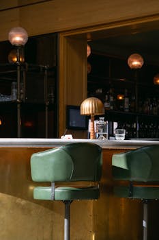 Cozy bar with green stools and vintage lighting, perfect for cocktail enthusiasts.
