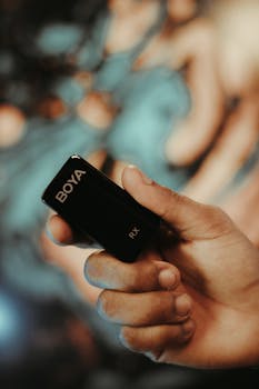 Close-up of a hand holding a Boya RX microphone indoor, ideal for content creators.