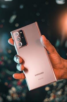 Close-up of a hand holding a modern smartphone with a bokeh background, showcasing sleek technology.