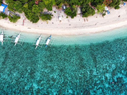 Free Stunning aerial view of boats moored along the turquoise shores of Panglao Beach in the Philippines. Stock Photo