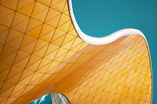 Close-up of curvy modern architecture against a blue sky, showcasing geometric patterns.
