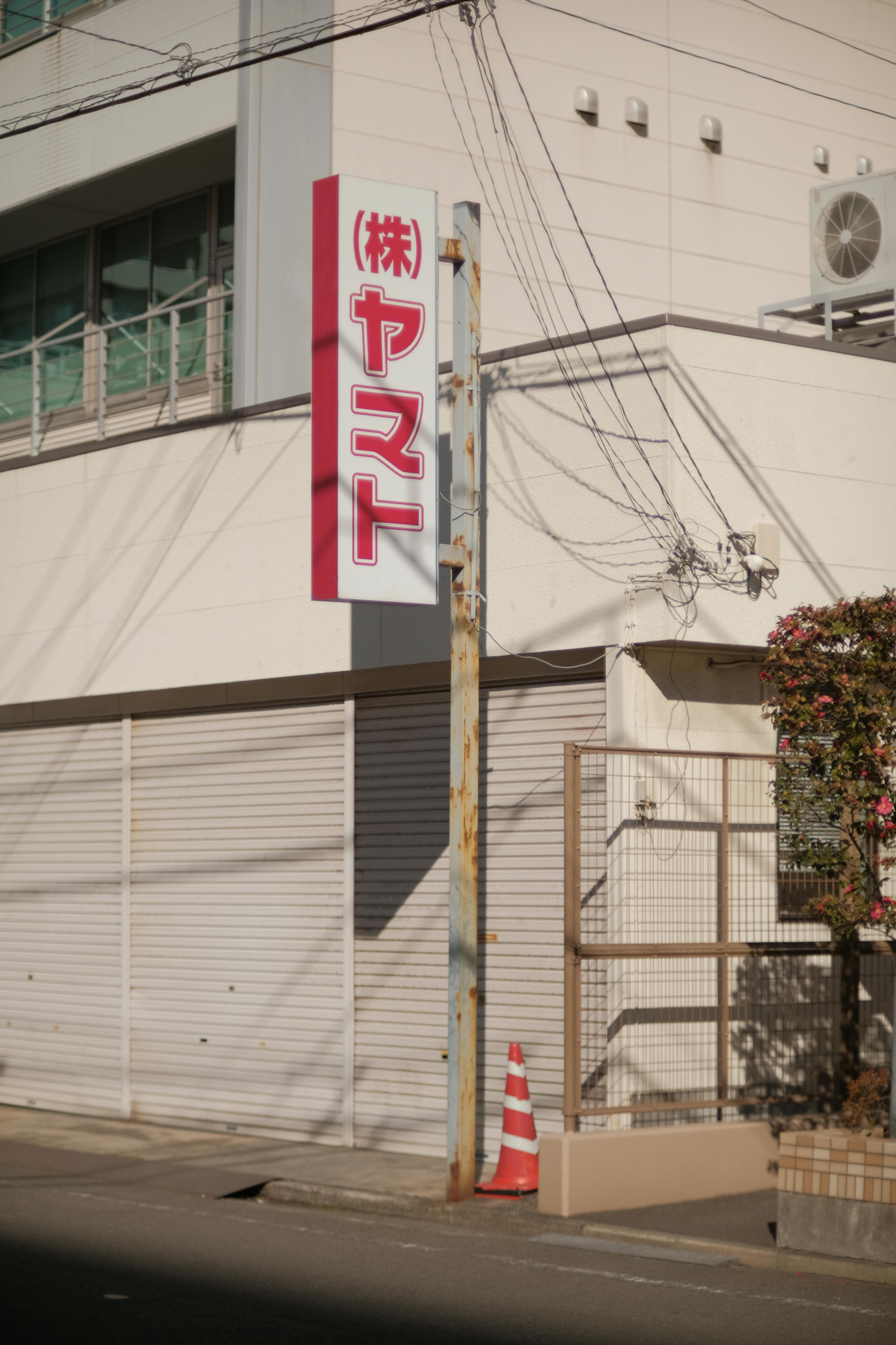 Sunlit urban street corner with Japanese signage and modern architecture.