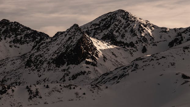 A stunning view of snow-covered rugged mountain peaks under a twilight sky.
