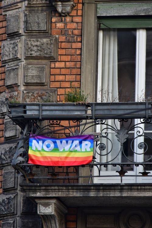 Free Colorful 'No War' banner on a vintage urban balcony against brick walls. Stock Photo