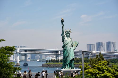 Free View of the Tokyo Bay replica of the Statue of Liberty with city skyline and visitors. Stock Photo
