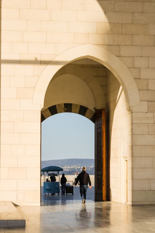 Free A person walking through a grand archway in Muscat, Oman, showcasing Arabian architecture. Stock Photo