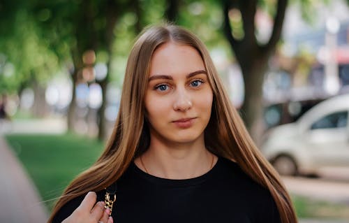 Photo of Young Woman with Long Straight Hair Posing in a Park