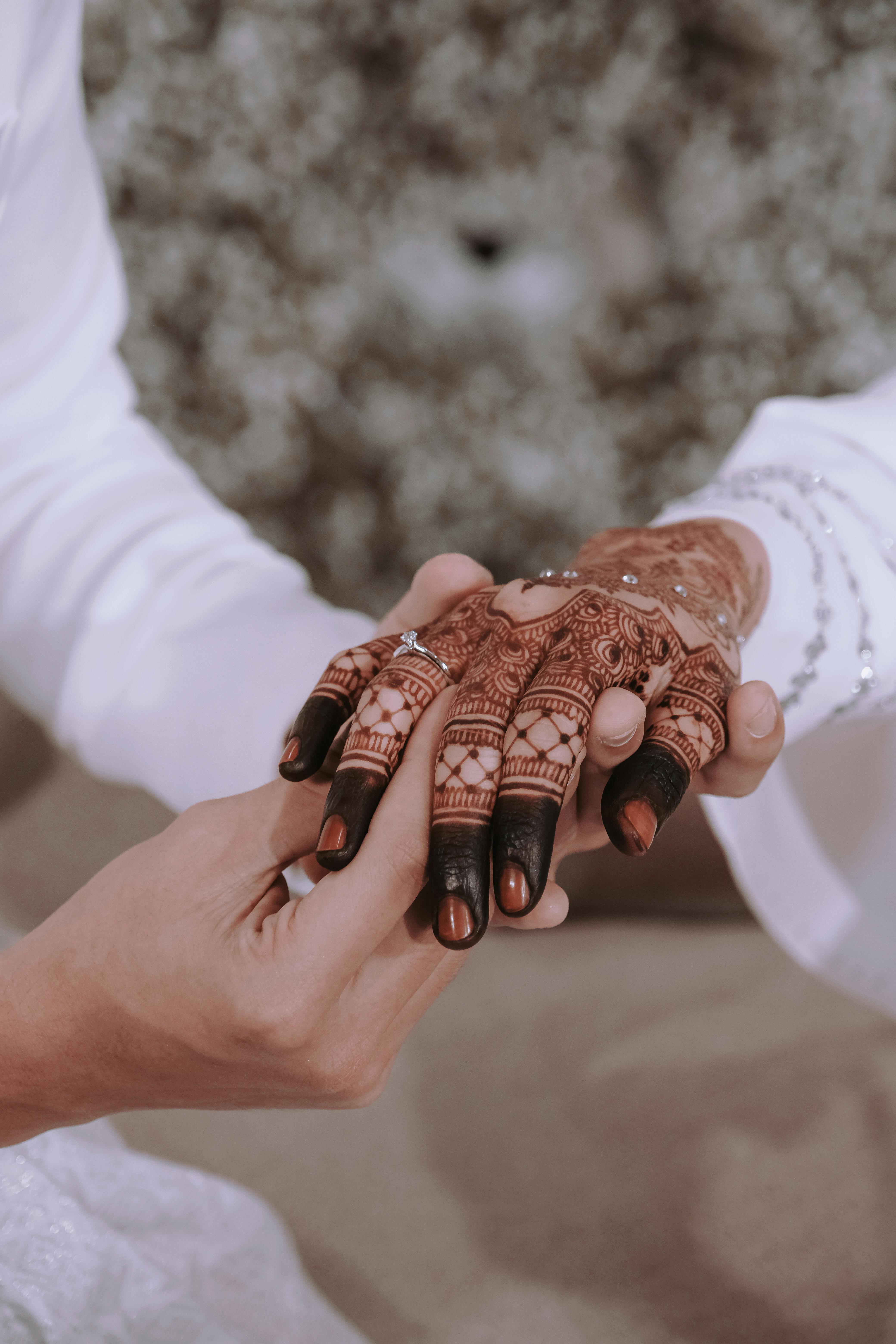 A bride and groom are holding hands with henna · Free Stock Photo