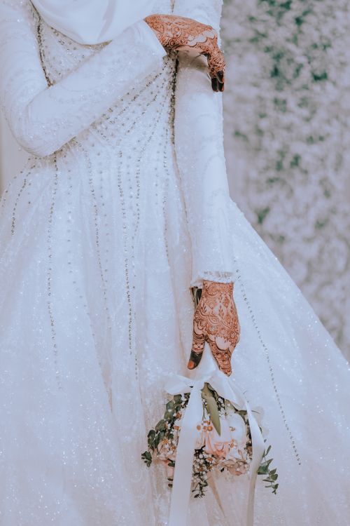 A muslim bride in a white dress holding a bouquet Free Stock Photo A muslim bride in a white dress holding a bouquet Free Stock Photo