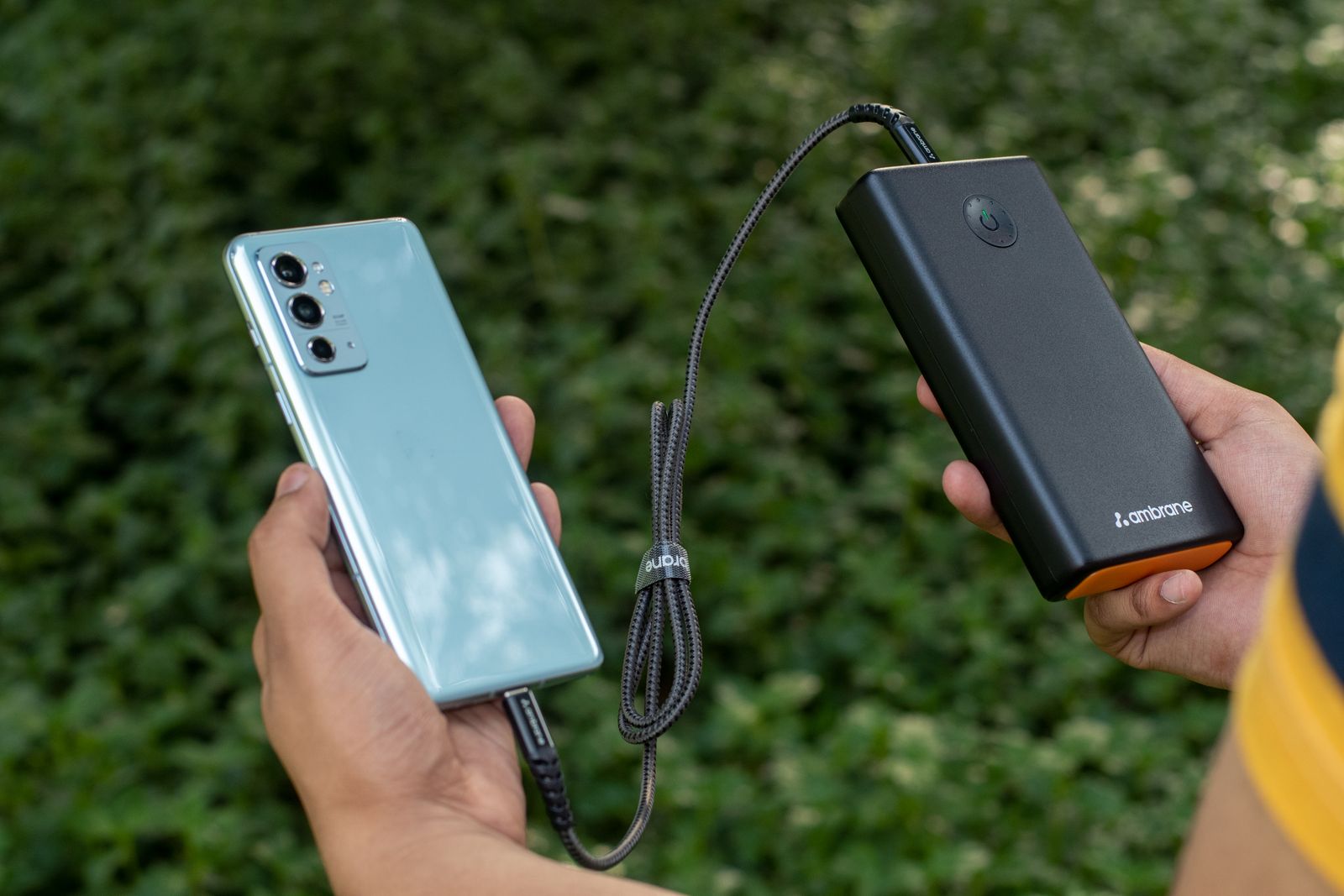 Person charging a smartphone with a portable power bank while working remotely