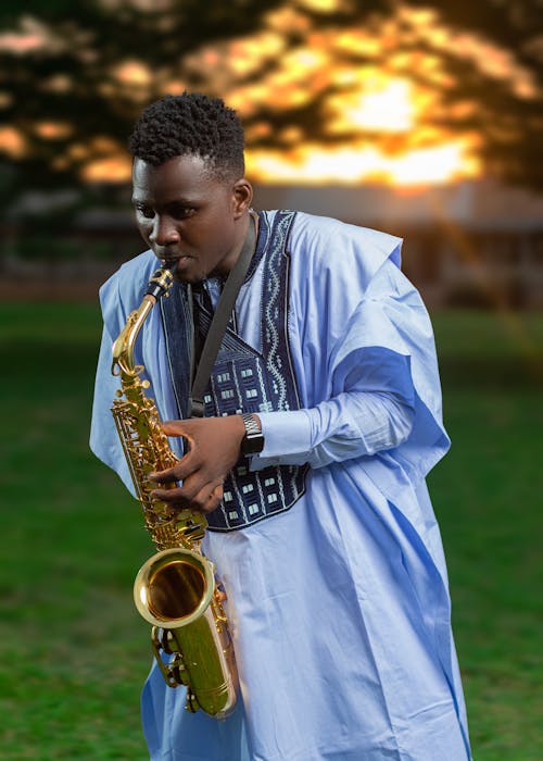 Black Man in Traditional Robe Playing on Saxophone