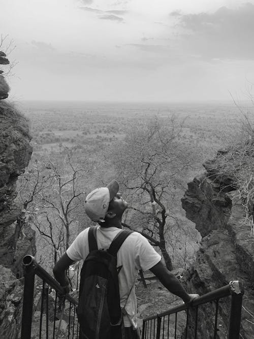 Black and White Shot of a Young Man with a Backpack Enjoying the Scenic Landscape View