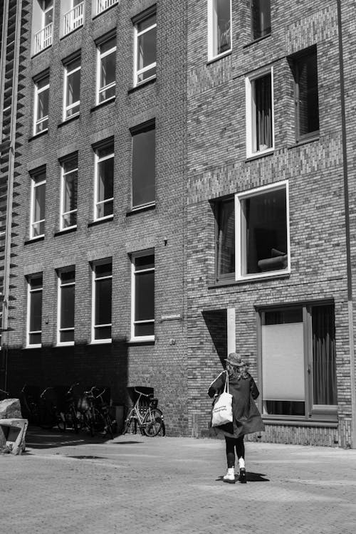 Woman Walking near Building Wall in Black and White