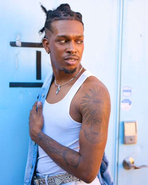 Man with Dreadlocks in Tattoos Posing near Doors