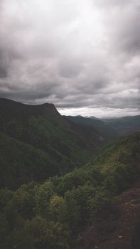 A stunning view of lush green mountains under a dramatic cloudy sky, perfect for nature enthusiasts.