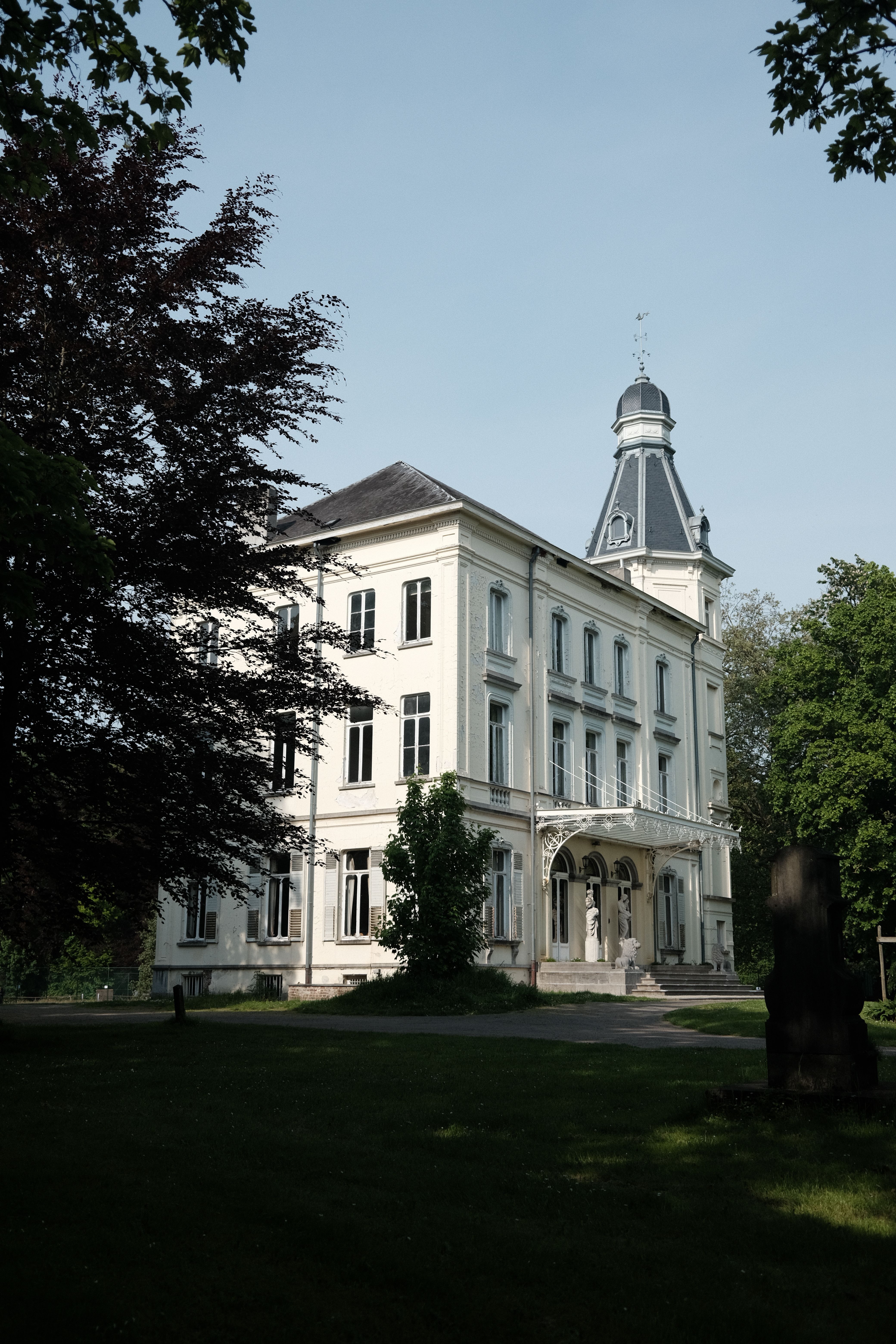 Serene view of a historic Belgian castle surrounded by greenery.